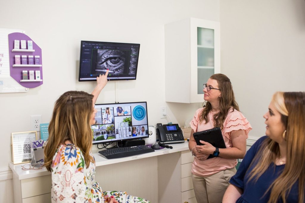 Dr. Denton explaining eye imaging on a monitor to a patient in the exam room