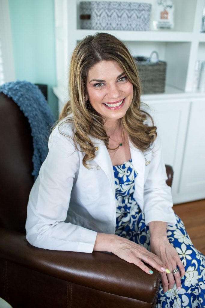 Dr. Melanie Denton, optometrist, smiling in a leather armchair at Salisbury Eyecare & Eyewear