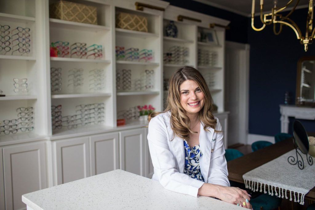 Dr. Denton seated in front of shelves of eyeglass frames at Salisbury Eyecare & Eyewear